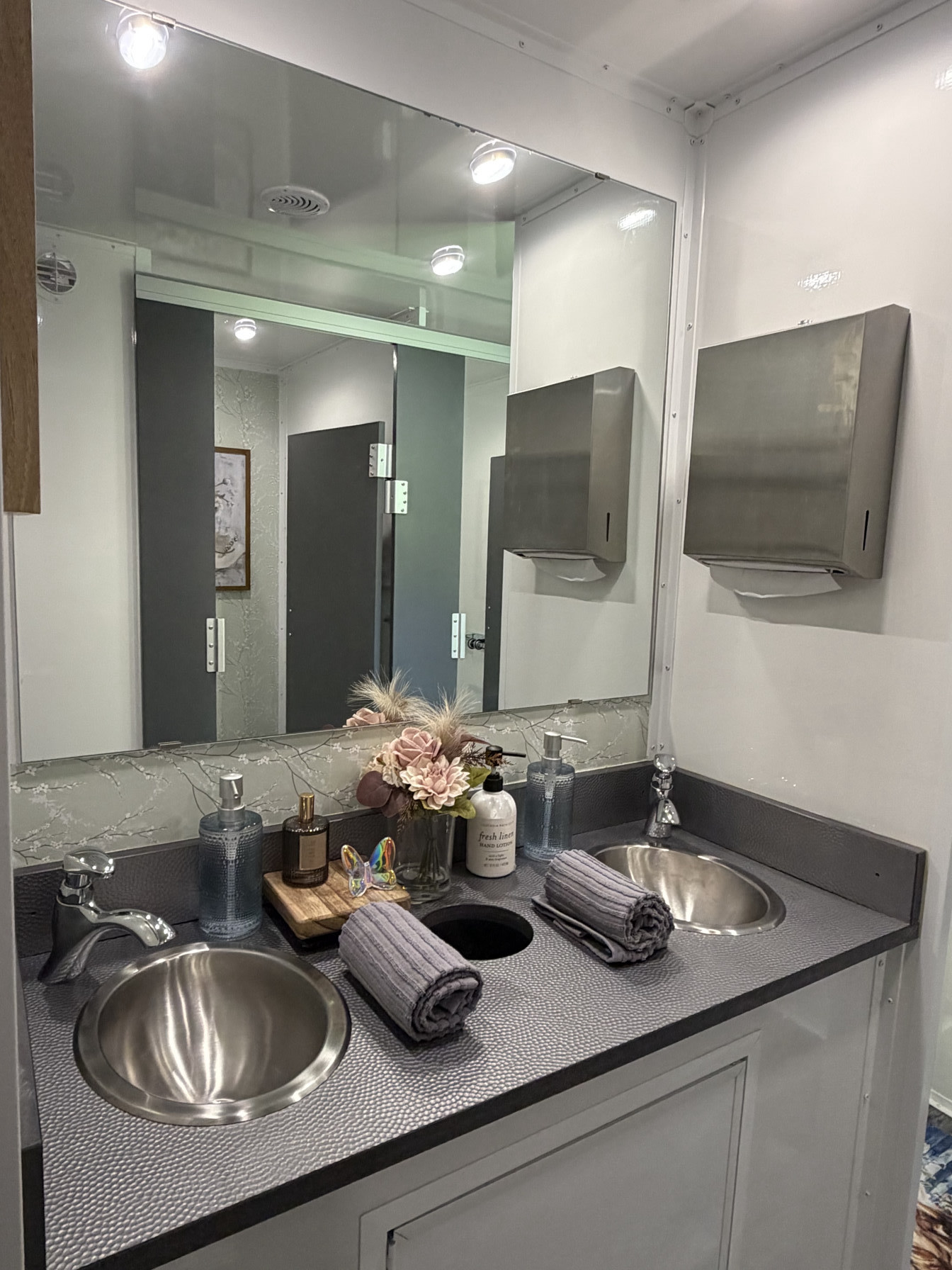 Private stations reflected in vanity mirror inside luxury restroom trailer